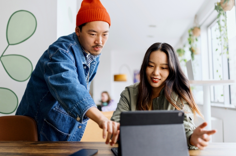 Two remote employees working together from a co-working space in Asia.