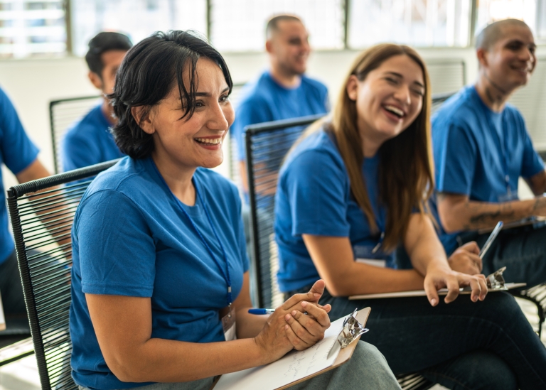 Nonprofit leaders in matching blue uniforms sit down for a team meeting.