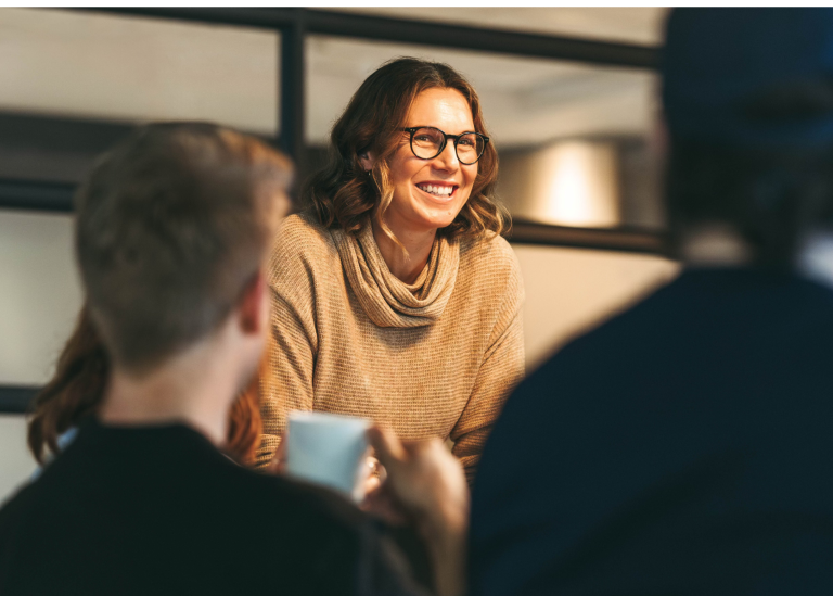 Focus on a woman in a room with others discussing global payroll best practices