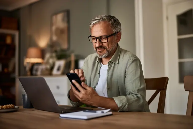 man-using-a-phone-while-working-over-a-laptop.jpg