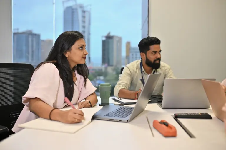 Co-workers-discussing-over-a-table-using-laptops.jpg