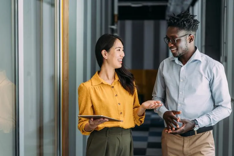 Two-colleagues-using-a-tablet-while-walking-in-office.jpg