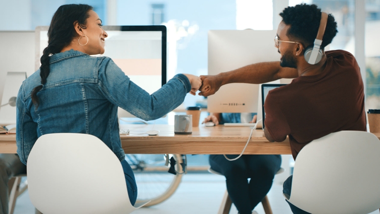 coworkers-at-desk-fist-bumping