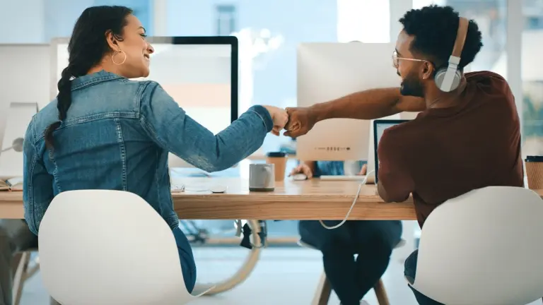 coworkers-at-desk-fist-bumping