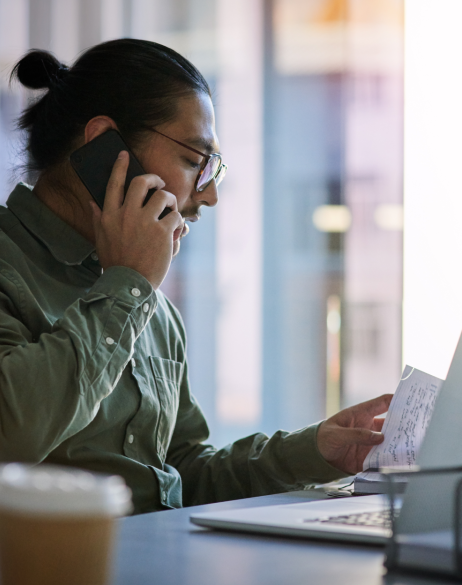 Man talking on the phone while looking at papers on his desk