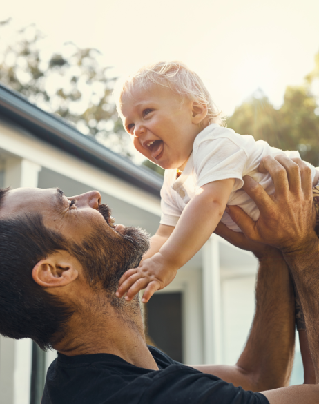 Father enjoying time off from work holding up his child in the air