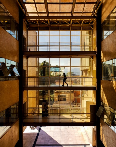 Zoomed out view of employee crossing 2nd level bridge in office building