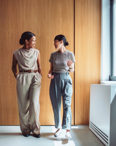 Female colleagues walking down a hallway discussing global M&A.