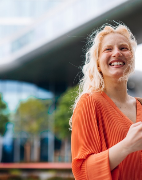 Smiling female employer holding phone outside while considering EOR contractor conversion.