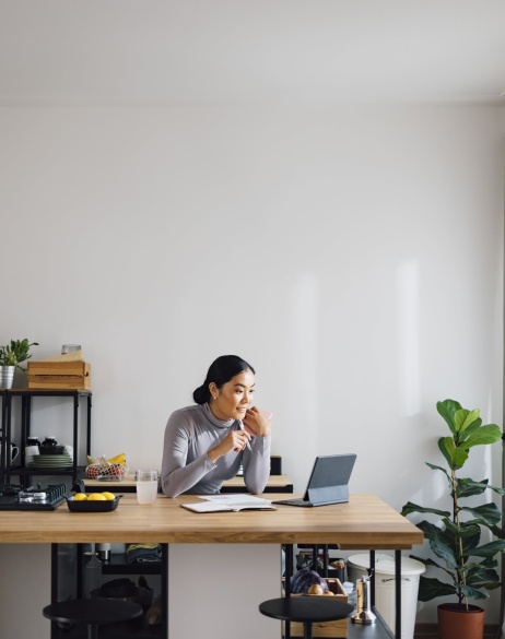 Woman sitting in small home kitchen taking notes on misclassification risk from tablet.