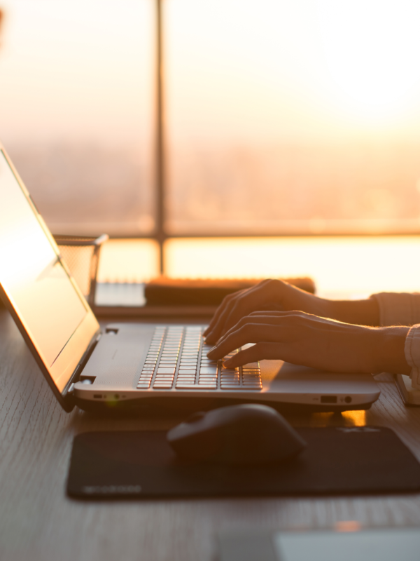 Laptop and mouse on a table with sunset in the background