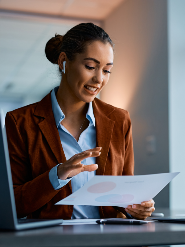 Woman talking through AirPods while looking at a sheet of paper