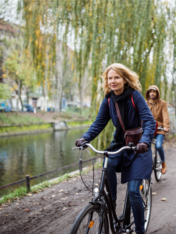 Woman riding bicycle along a river path