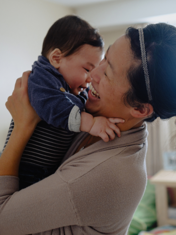 Asian woman holding baby up to her chest