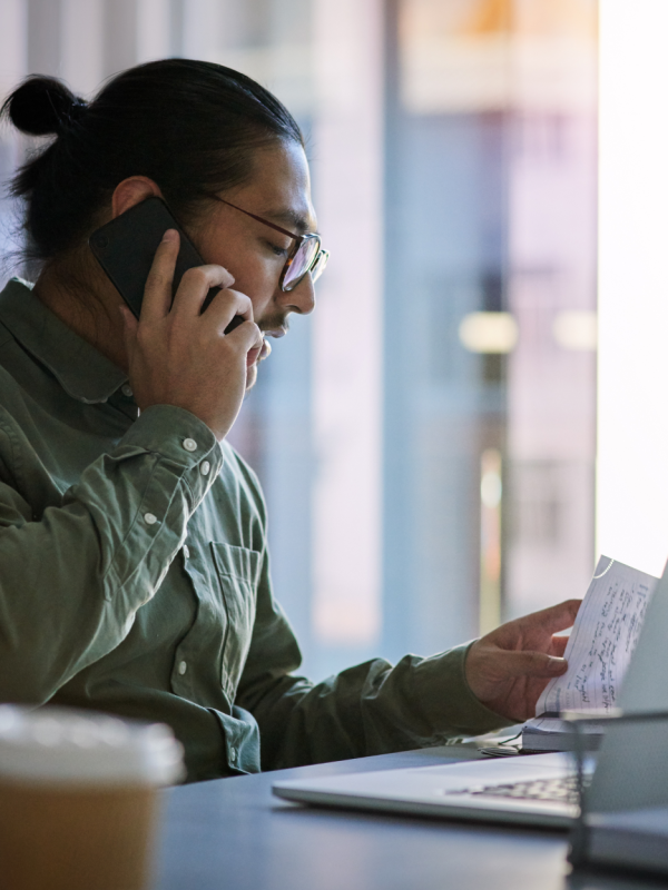 Man talking on the phone while looking at papers on his desk