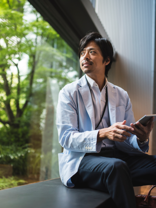 Man on device sitting on window sill looking outside