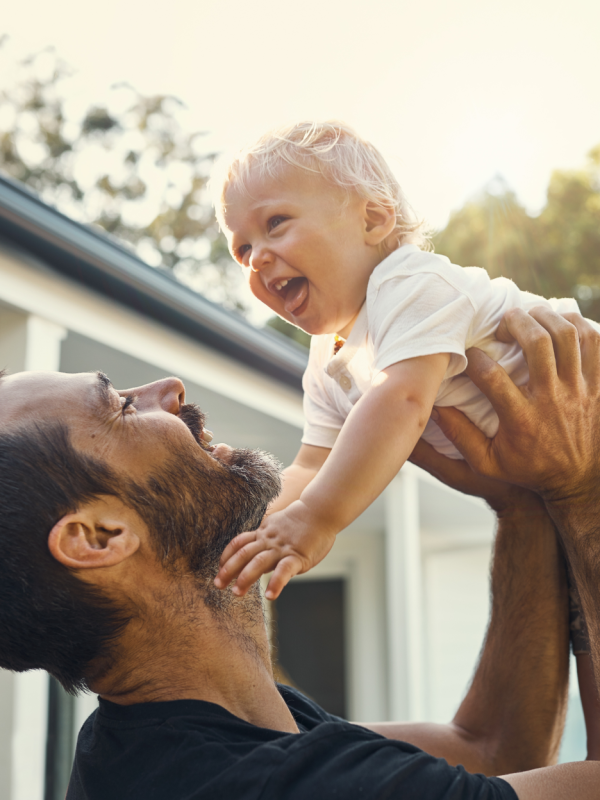 Father enjoying time off from work holding up his child in the air