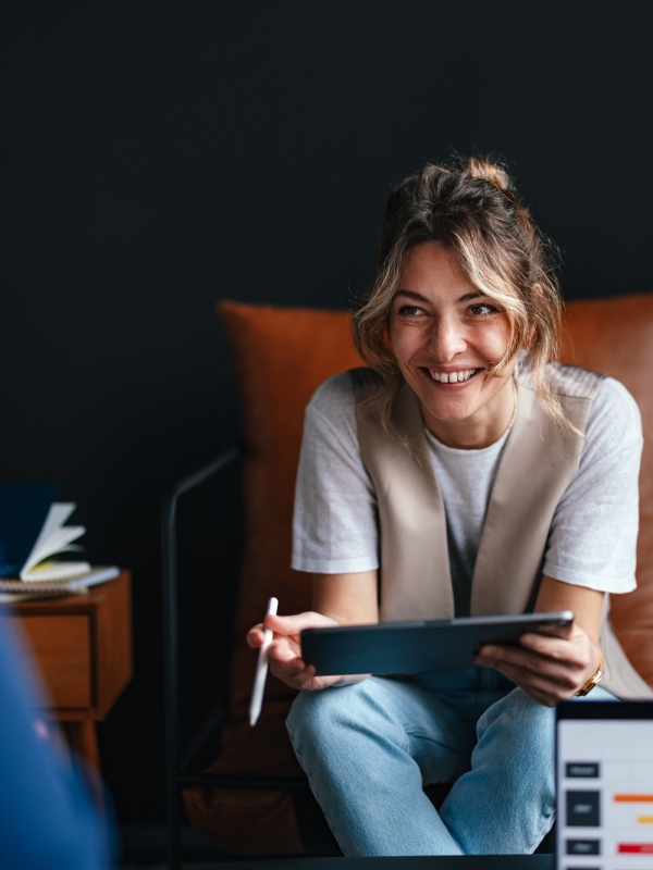 Woman holding tablet during team meeting discussing HR compliance.