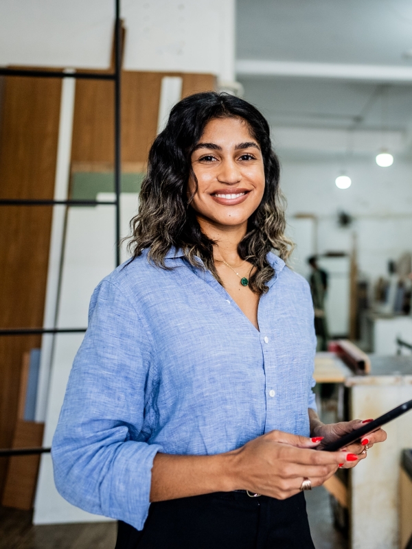 Female employer smiling at the camera while holding a tablet.