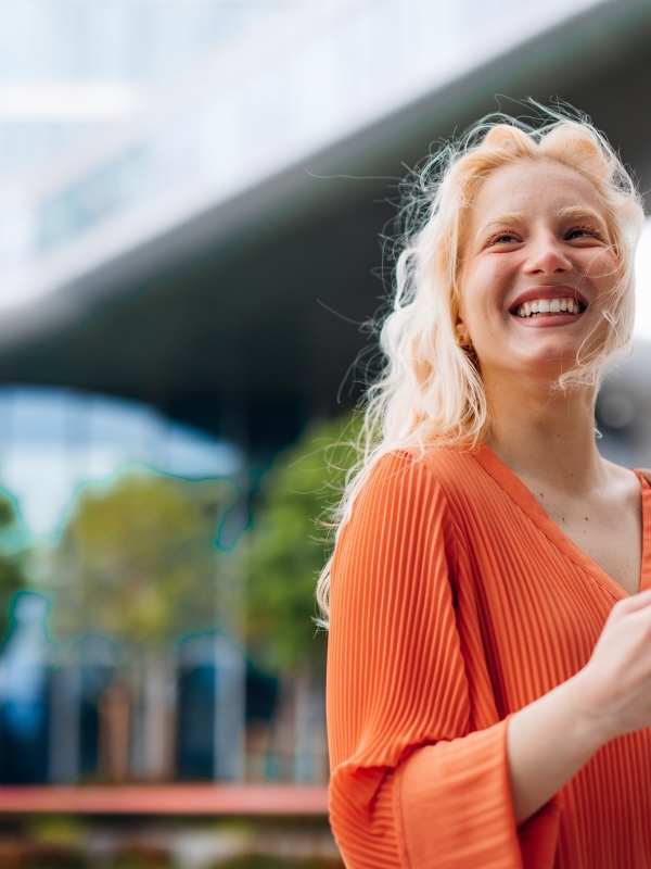 Smiling female employer holding phone outside while considering EOR contractor conversion.