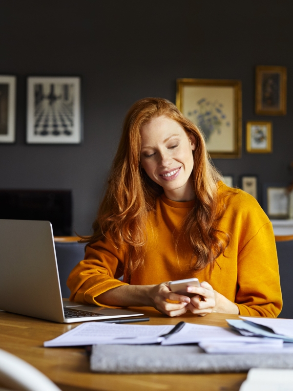 Female employer reviewing Pebl M&A services on laptop and phone while working from home.