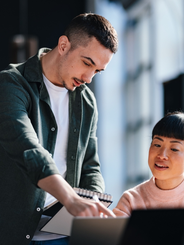 Two colleagues analyzing global expansion costs on computer.