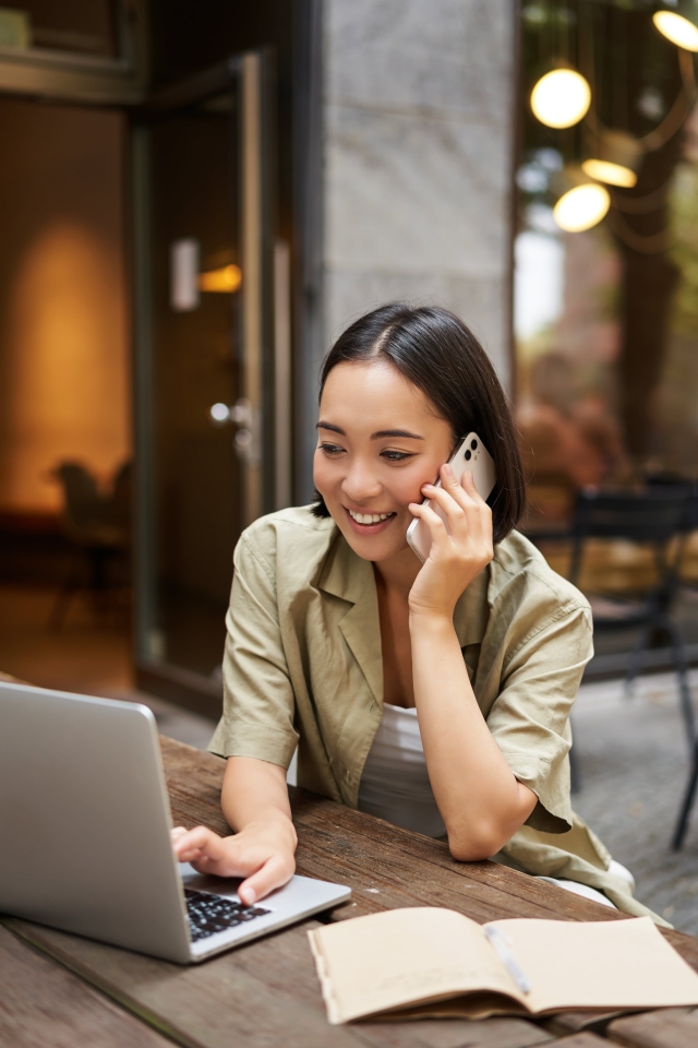 Woman on phone while looking at laptop of global hiring options with Pebl EOR.