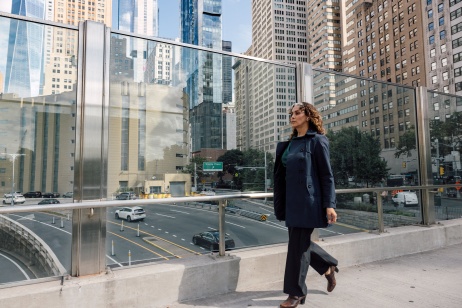 Woman walking on bridge across highway to downtown office