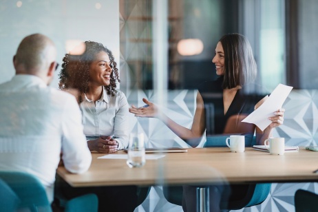 Two woman smiling and talking in meeting table