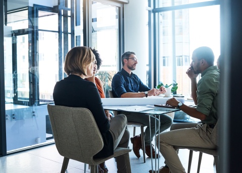 HR team discusses merger and acquisition issues in office space lit by natural light.