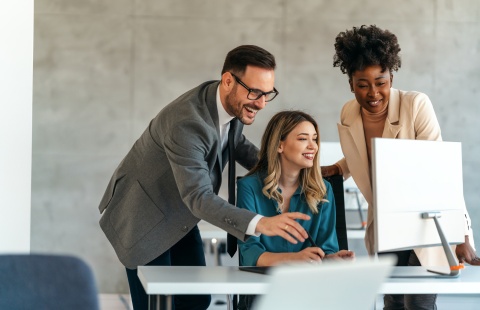 Colleagues showing another colleague how to send crypto payments via desktop computer