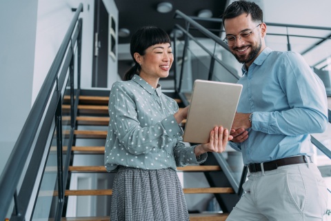 Two coworkers reading about small business employee benefits on a tablet