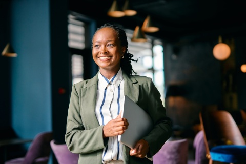 Smiling businesswoman in Cameroon holding a laptop
