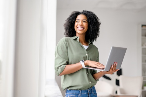 Smiling woman holds laptop while working from home in Bermuda