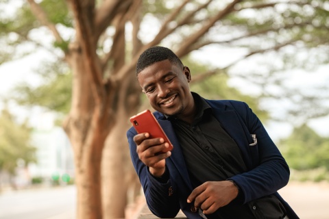 Man smiling and texting on his phone in Nigeria