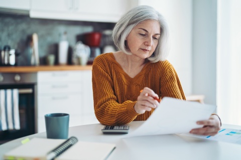 Mature woman sitting at table analyzing payroll taxes in Luxembourg