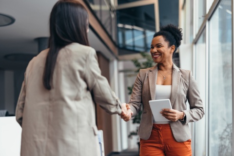 Two businesswomen shaking hands after discussing salary in Malawi