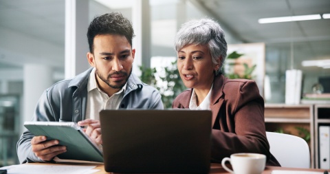 Two business people working with a tablet and laptop in an office