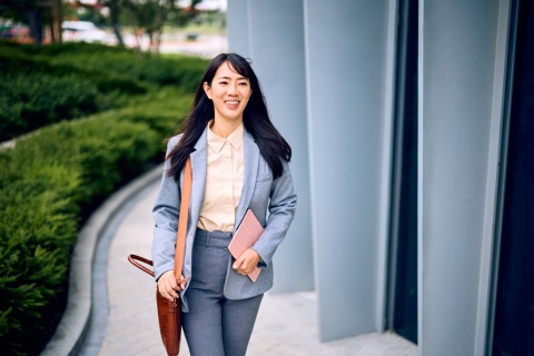 Businesswoman walking outside of office building in Cambodia holding a tablet