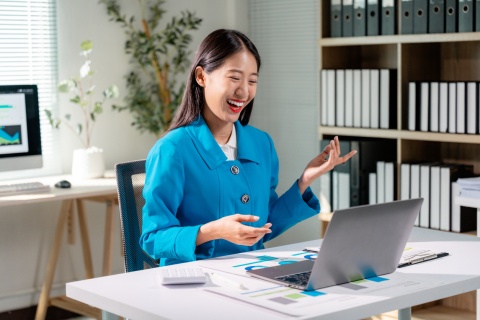 Businesswoman wearing a blue suit sits at her office desk in Laos