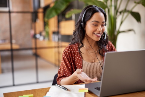 Woman smiling and working on a laptop during a video call