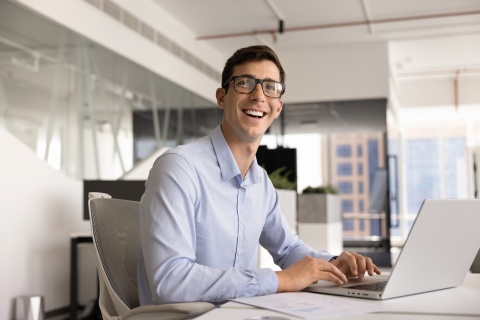 Smiling man in glasses typing on laptop in the Czech Republic