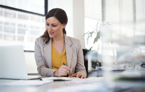 Woman making notes at her desk while using her laptop in Afghanistan