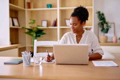Woman taking notes while calculating payroll taxes in Malawi