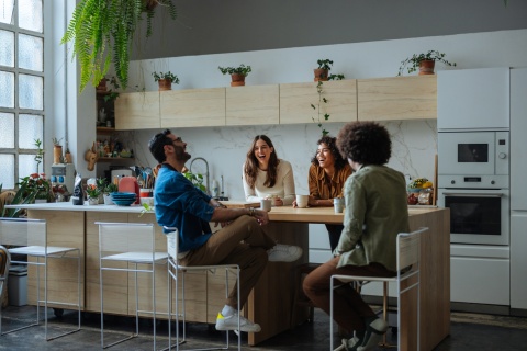 Cheerful friends laughing and sitting in a modern kitchen
