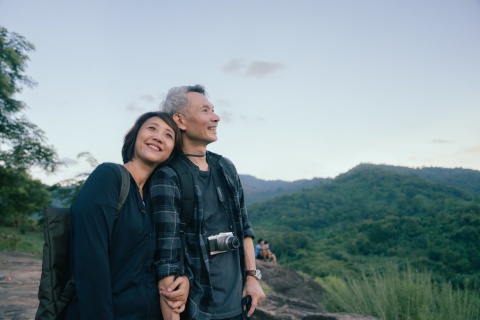 Happy Asian couple hikers on top of a mountain