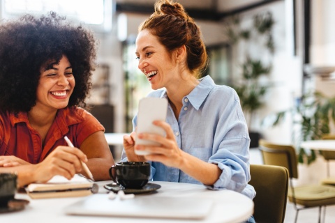 Happy female colleagues reading a text message on a smartphone
