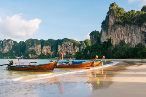 Longtail boats on the beach by Krabi Cliffs in Thailand