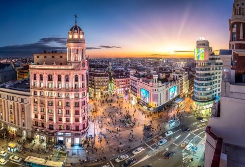 Madrid Gran Via during sunset showcasing illuminated historic building