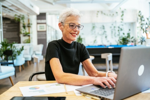 Senior woman working in modern office using laptop